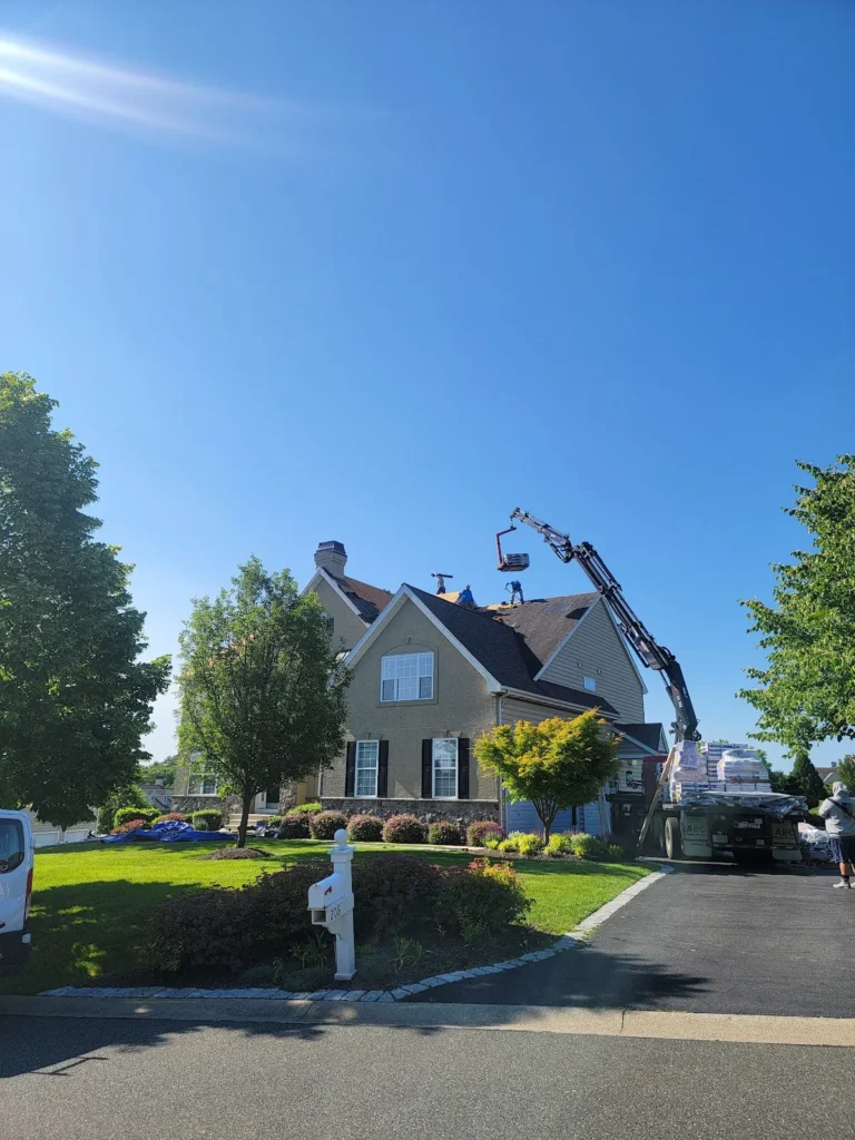 A roofing contractor in Havre De Grace, MD uses a boom crane to load materials onto a residential roof.